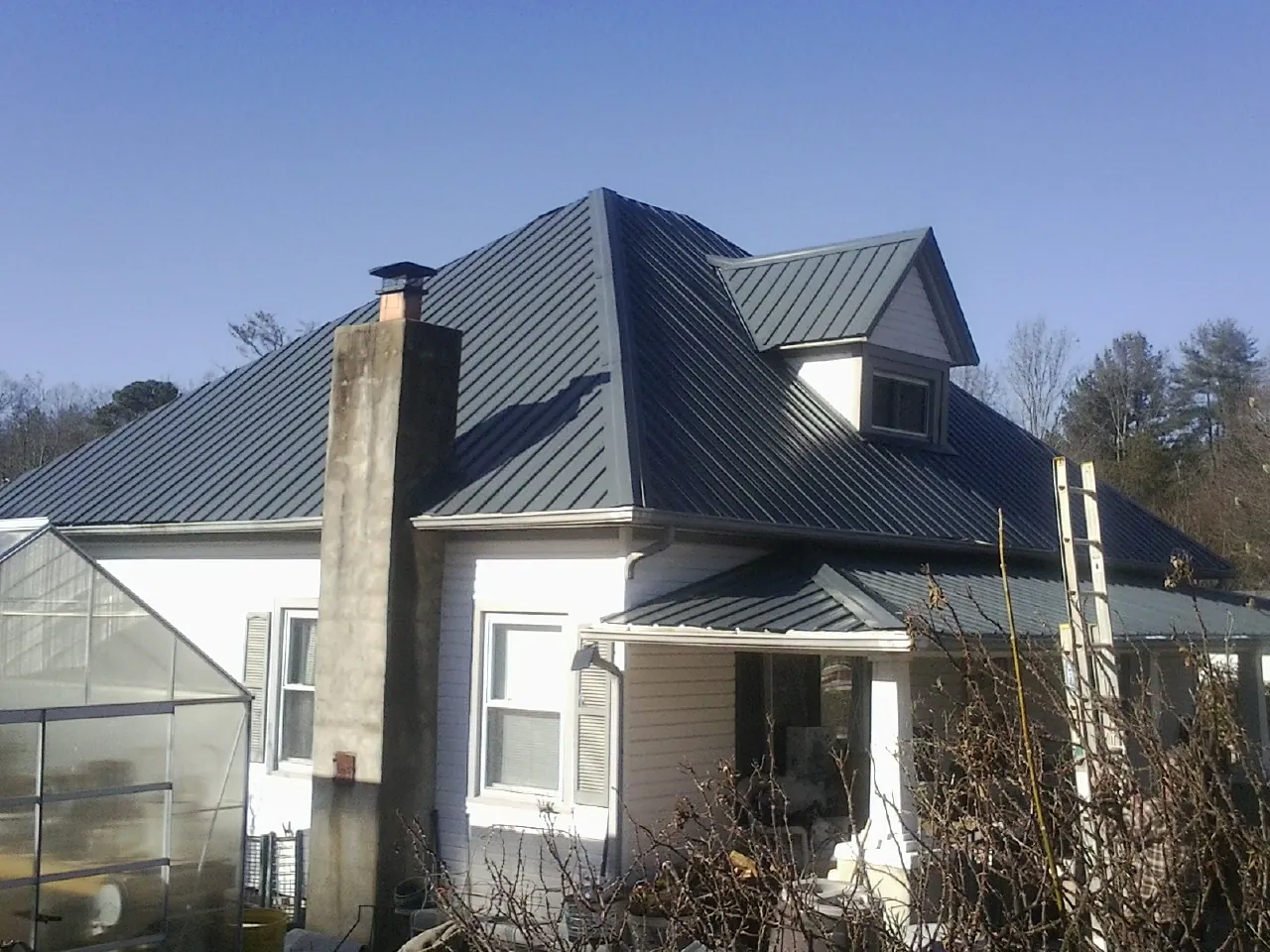 Dark blue standing seam metal roof on a white farmhouse with dormer — Slate & Tile Roof Repair by Roofing Brothers in Livermore