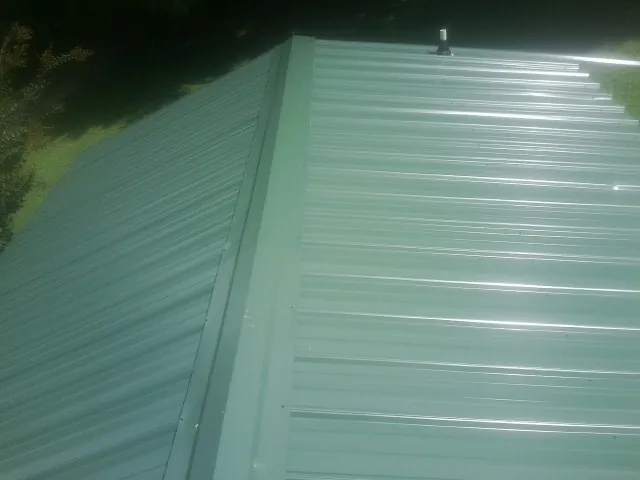 New green metal panels meeting at the ridge of a roof — Flat Roof Repair work by our crew in Livermore
