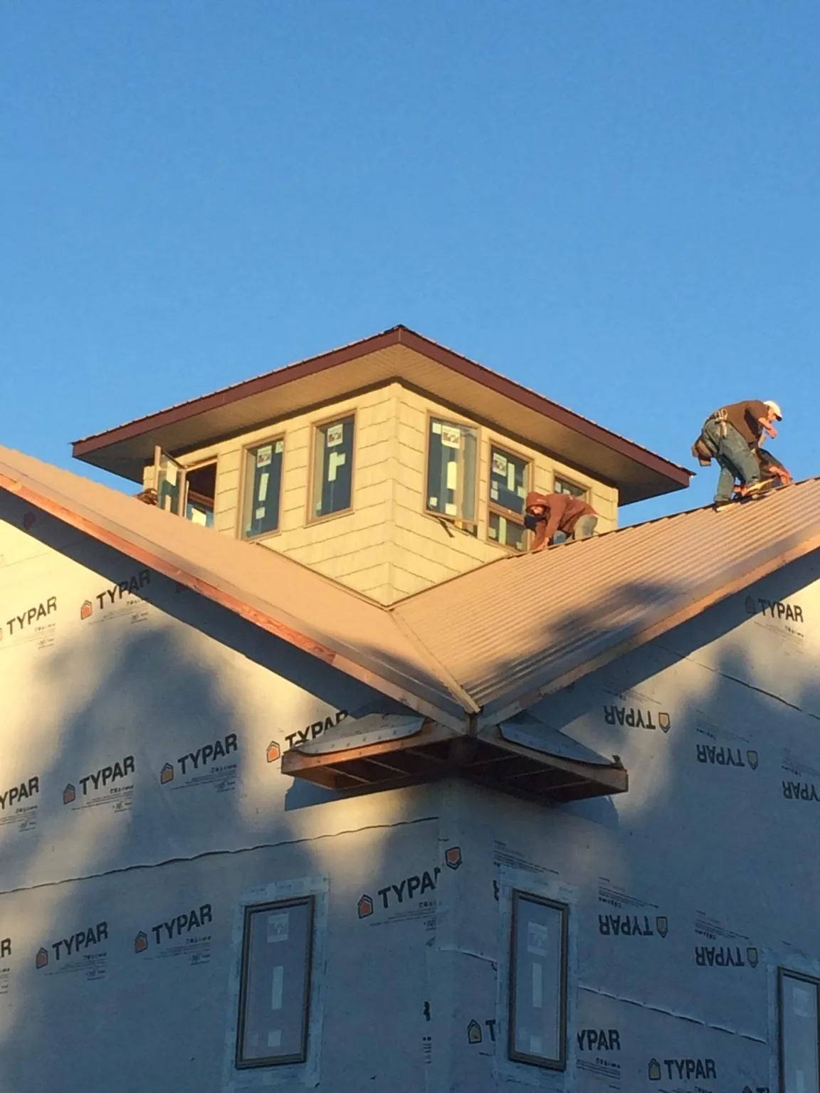 Roofers working around a rooftop cupola on a new metal roof at sunset — Roof Waterproofing in Livermore by Roofing Brothers